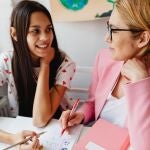 Profesora corrigiendo a su alumna con un bolígrafo rojo