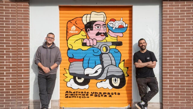 Propietario de L'Artigiano junto al artista que ha pintado su cierre en una campaña de Just Eat. David Jar