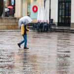 Un hombre se protege con un paraguas de la lluvia en León