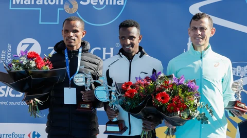 El atleta etíope Selemon Barega (c), oro, su compatriota Adisu Wegene (i), plata, y el marroquí Mohamed Reda El Aaraby (d), bronce, en el podio de la competición masculina en la cuadragésima edición del Maratón de Sevilla, este domingo en la capital andaluza
