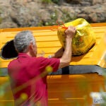 Un señor deposita envases en el contenedor amarillo