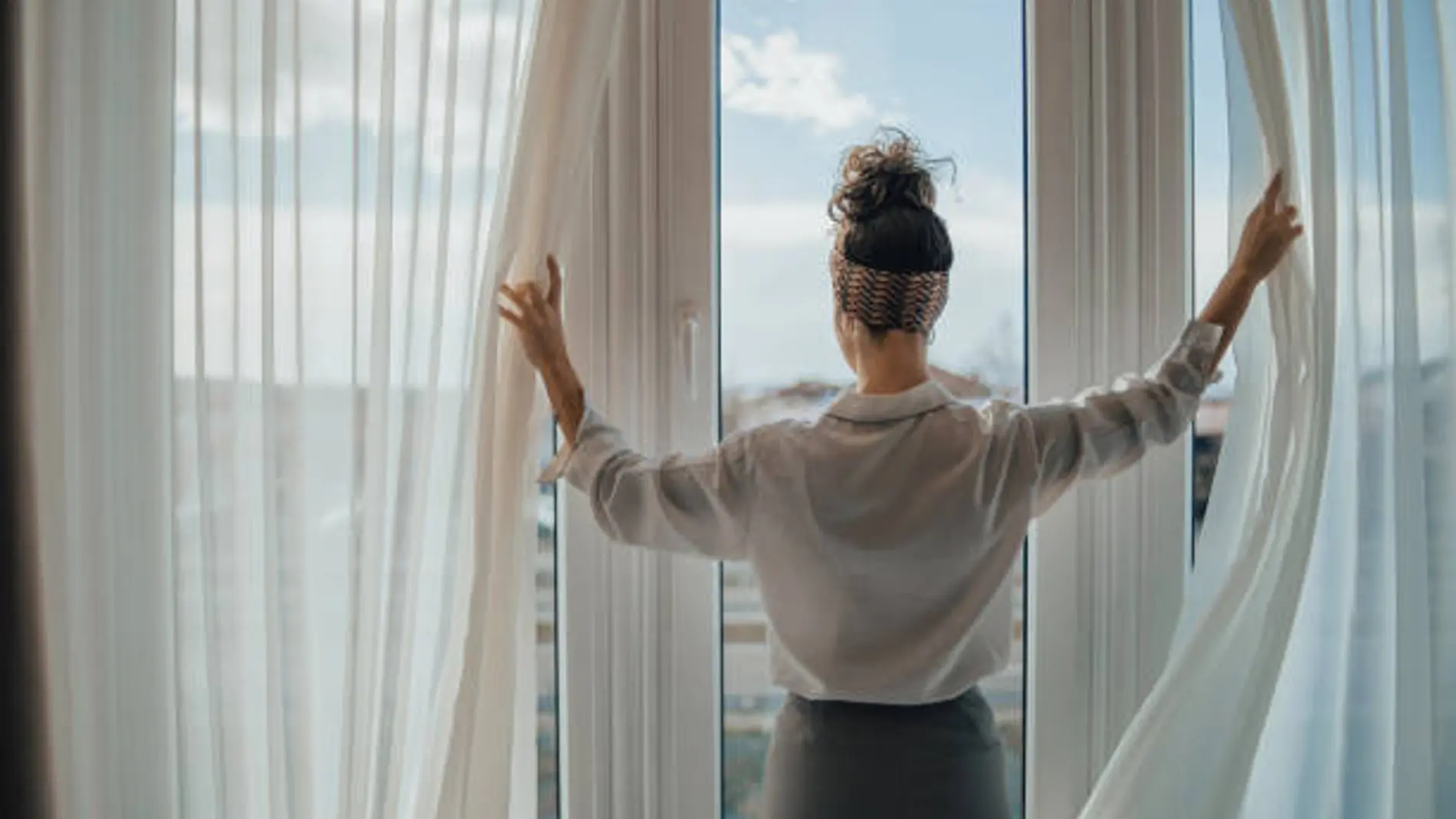 Imagen de archivo de una mujer corriendo unas cortinas