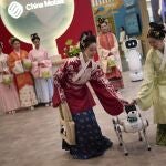 A dog-shaped robot manufactured by China Mobile Home Service Robots stands next to representatives of the company, during its presentation at the Mobile World Congress in Barcelona, Spain, Monday, March 3, 2025. (AP Photo/Emilio Morenatti)