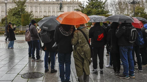 Un grupo de turistas se protegen de la lluvia con sus paraguas en el centro de Madrid.