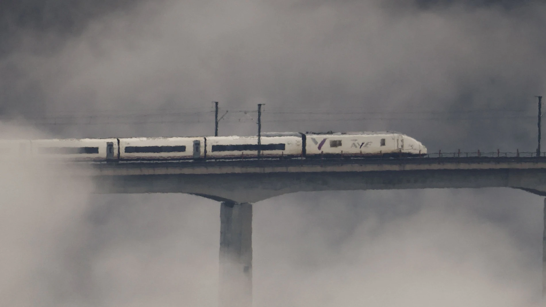 Un tren Ave pasa por el viaducto de Eixo cubierto por la niebla, en Santiago de Compostela.