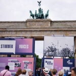 Espectadores observan paneles informativos y fotos históricas frente a la Puerta de Brandeburgo en Berlín