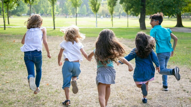 Grupo de niños corriendo juntos sobre la hierba, con carrera en el parque