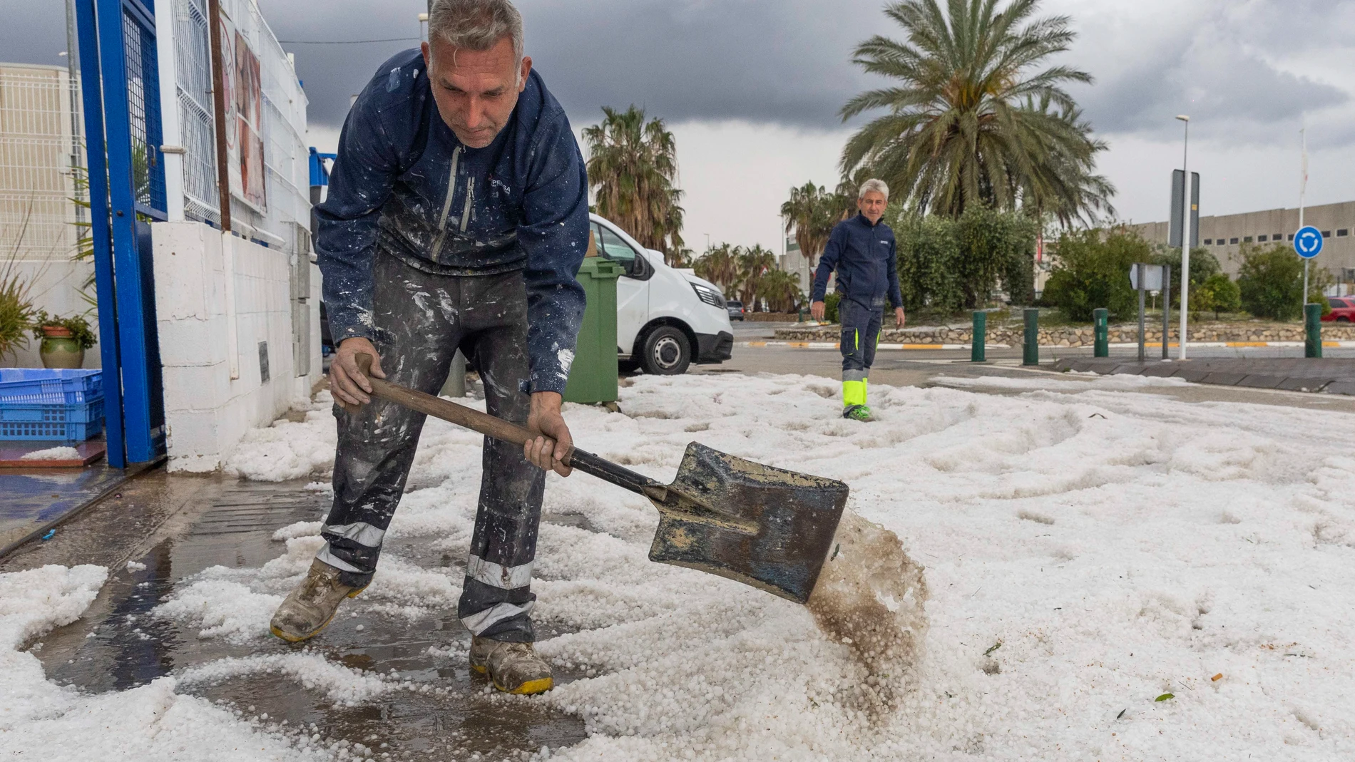 MULA (MURCIA), 08/05/2025.- Un hombre retira el granizo de la puerta de su empresa este jueves en el Polígono Industrial de El Arreaque del municipio de Mula, tras la tormenta de granizo que ha caído en los municipios de Mula, Bullas, Calasparra y Cehegín. La autovía del noroeste se ha cortado un tiempo un carril por sentido hasta que el granizo acumulado ha sido retirado con quitanieves autonómicos. EFE/Marcial Guillén