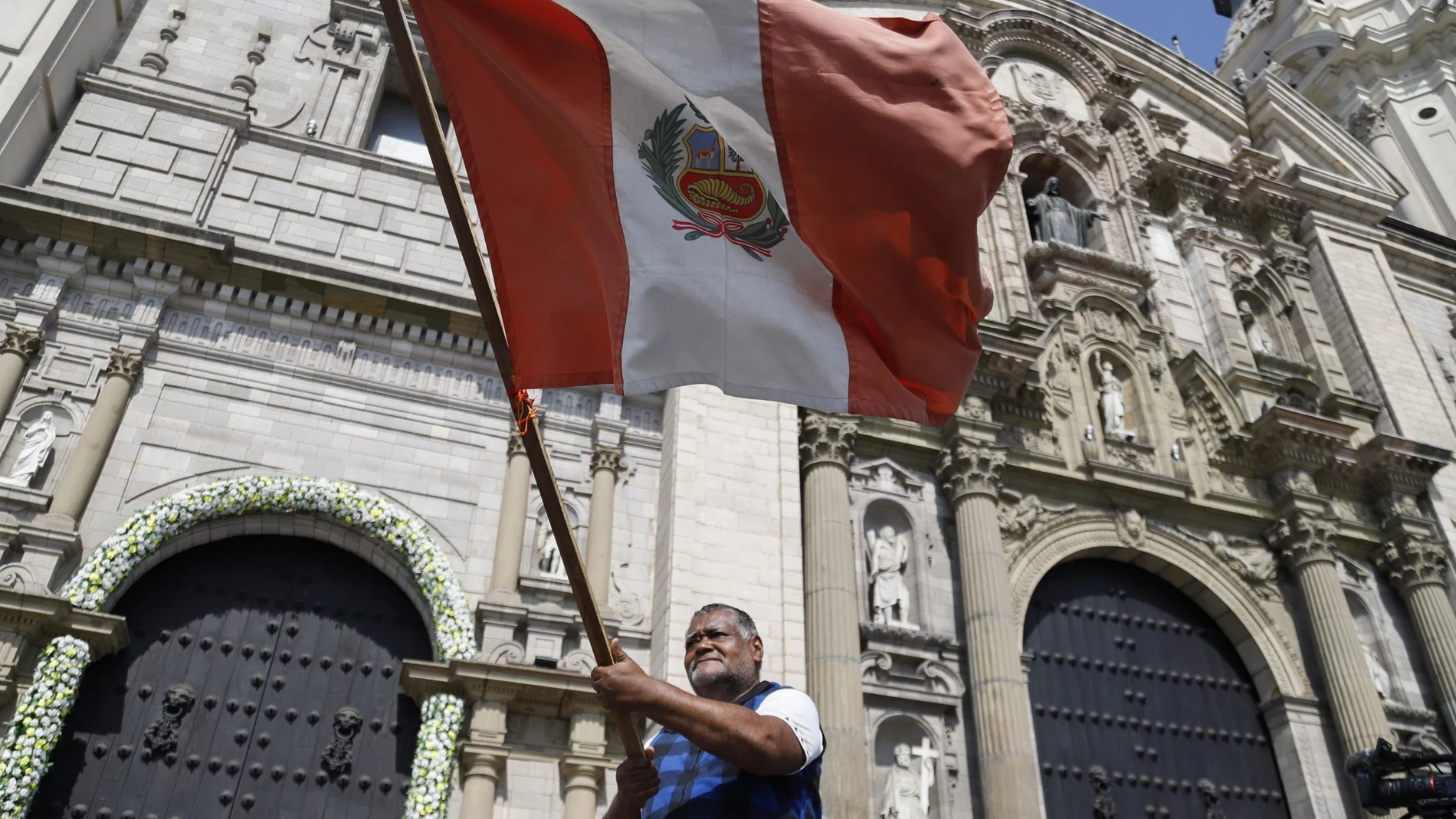 FOTODELDÍA AME5855. LIMA (PERÚ), 08/05/2025.- Un hombre ondea una bandera de Perú frente a la Catedral de Lima, luego de la elección del papa León XIV, este jueves, en Lima (Perú). El cardenal peruano Pedro Barreto afirmó que la iglesia Católica tiene "un papa que realmente quiere al Perú", al destacar la elección del estadounidense nacionalizado peruano Robert Prevost como el papa León XIV, tras las palabras de reconocimiento que hizo a la ciudad norteña de Chiclayo al dirigirse a los fieles...