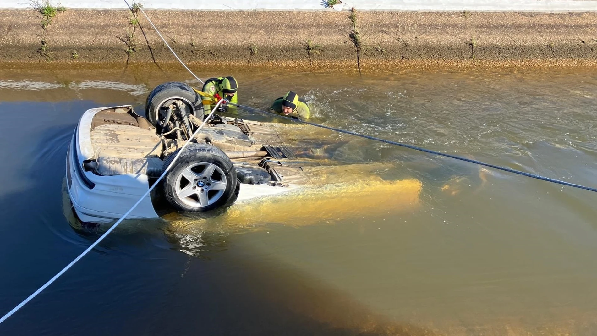 Bomberos rescatando el coche hundido en un canal de Cartaya