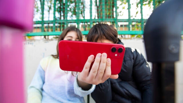Niños con el teléfono móvil a la puertas de un colegio. 