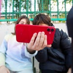 Niños con el teléfono móvil a la puertas de un colegio. 