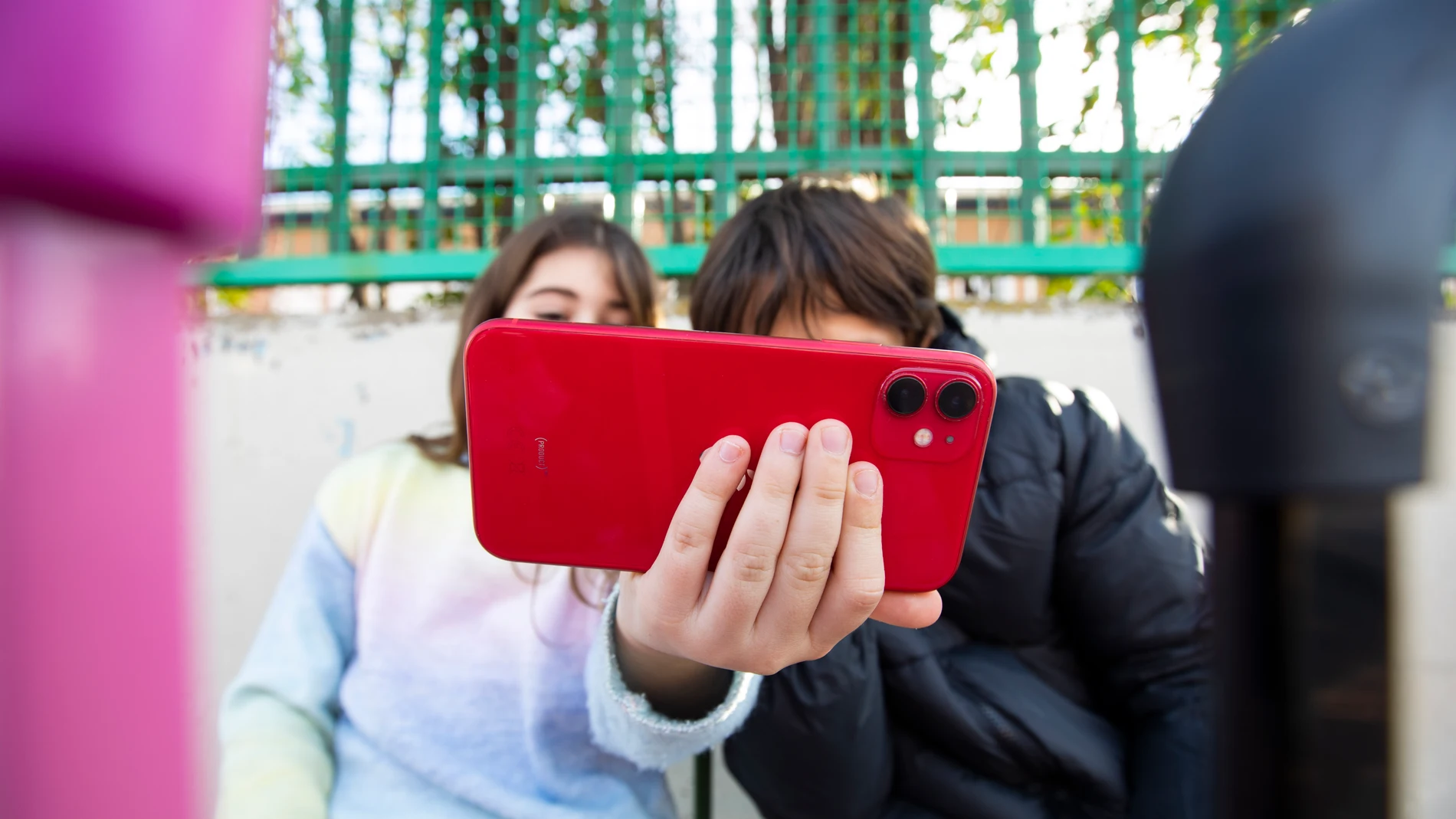 Niños con el teléfono móvil a la puertas de un colegio.