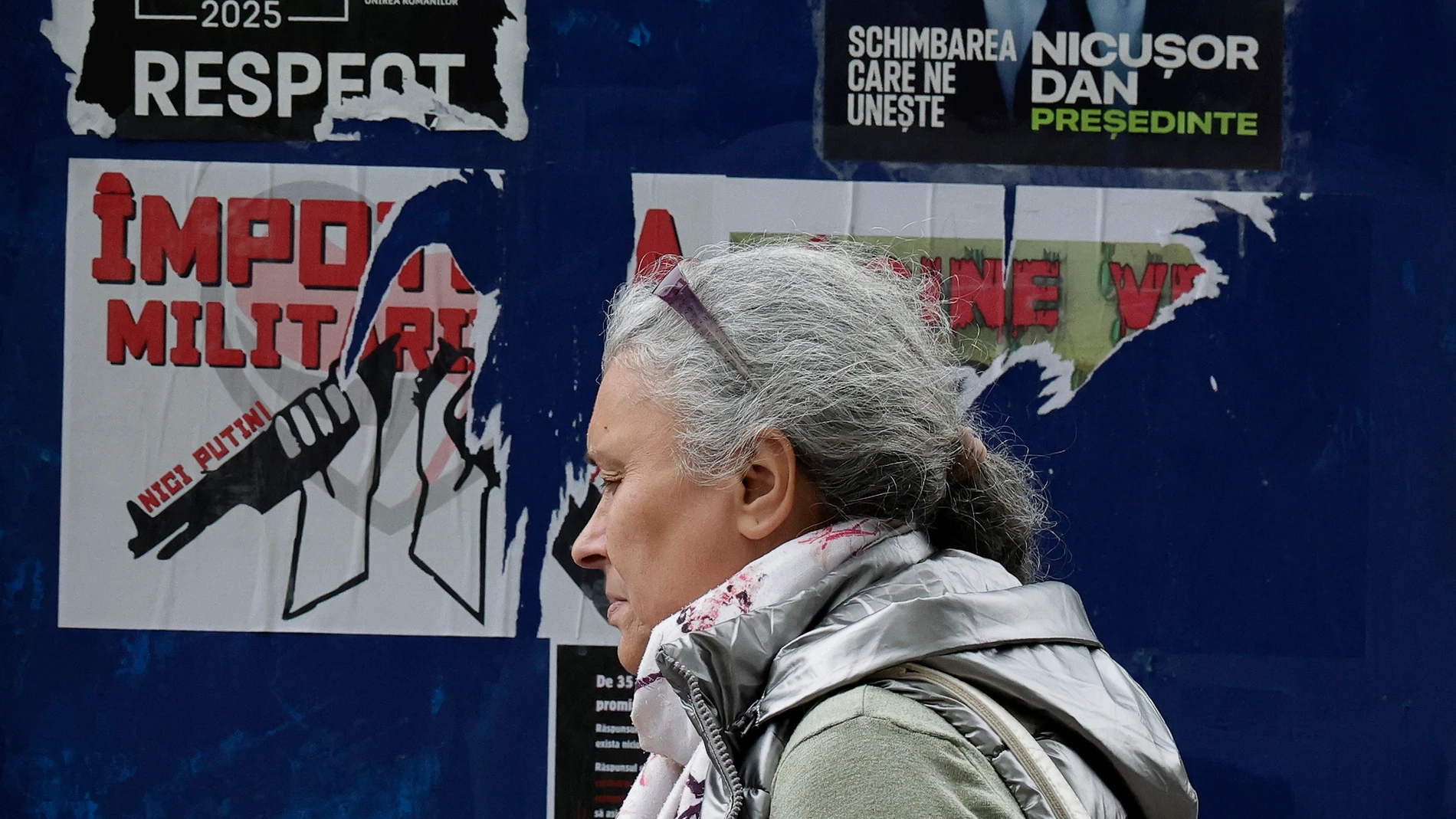 Bucharest (Romania), 16/05/2025.- A woman passes by a billboard displaying electoral posters of the candidates for the runoff of the 2025 presidential election, in Bucharest, Romania, 16 May 2025. The runoff for the 2025 Romanian presidential election will be held on 18 May between AUR party leader George Simion, who won the first round of the Romanian election rerun with 40.96 percent of the vote, and mayor of Bucharest Nicusor Dan. (Elecciones, Rumanía, Bucarest) EFE/EPA/ROBERT GHEMENT