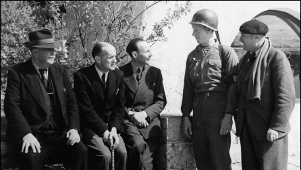 Un policía militar conversa con François de La Rocque, Jean Borotra y Marcel Granger tras ser rescatados (sentados y de izda. a dcha.)