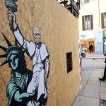 People walk past a mural titled 'The American Dream', created by the Italian artist aleXsandro Palombo for Pope Leo XIV, after it was unveiled at the entrance to the 15th-century church Santa Maria presso San Satiro, in Milan, Italy, 16 May 2025. 