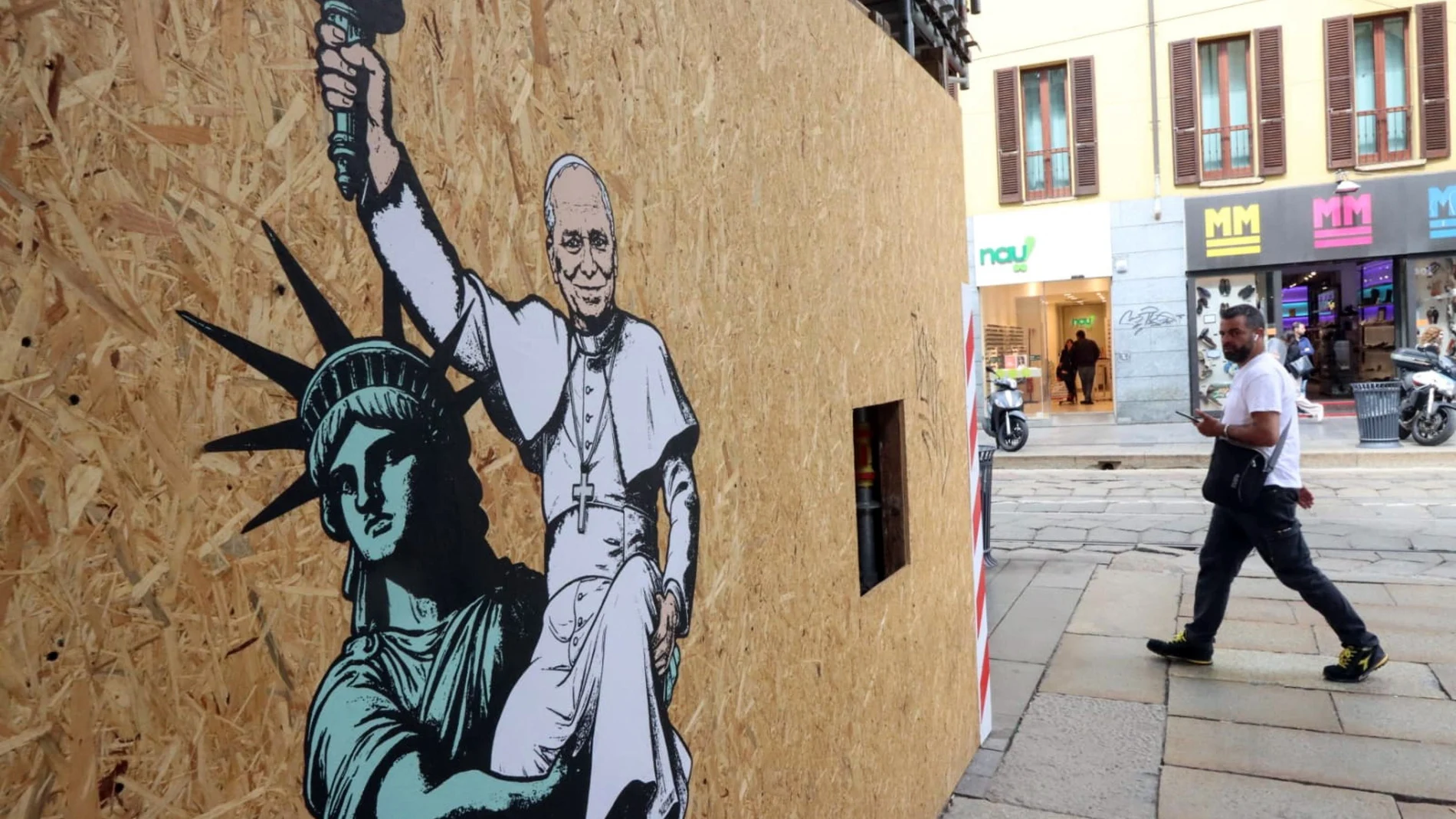 People walk past a mural titled 'The American Dream', created by the Italian artist aleXsandro Palombo for Pope Leo XIV, after it was unveiled at the entrance to the 15th-century church Santa Maria presso San Satiro, in Milan, Italy, 16 May 2025.