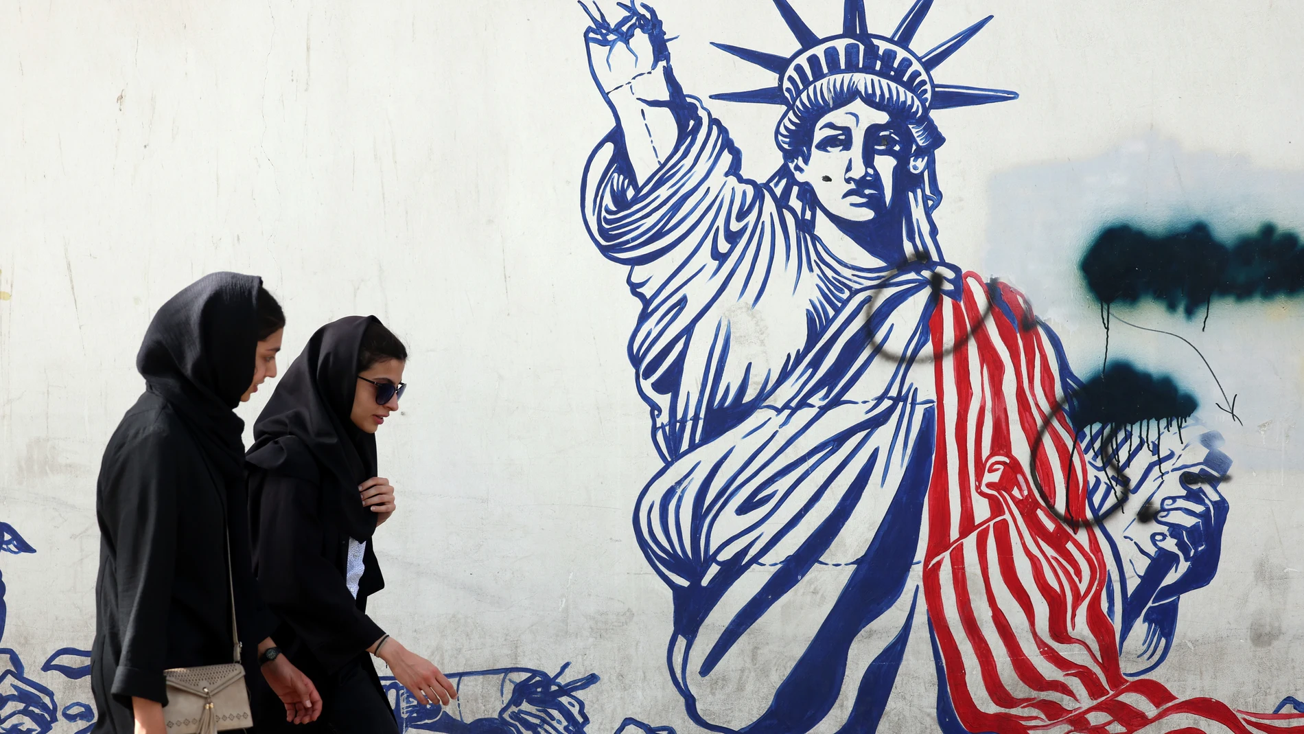 FOTODELDÍA TEHERÁN (IRÁN), 22/05/2025.- Mujeres iraníes caminan junto a un mural antiestadounidense cerca de la antigua embajada estadounidense en una calle de Teherán, Irán, este jueves. El Ministerio de Asuntos Exteriores iraní anunció que Irán y EE. UU. celebrarán su quinta ronda de conversaciones en Roma, Italia, el viernes 23 de mayo de 2025.-EFE/ Abedin Taherkenareh