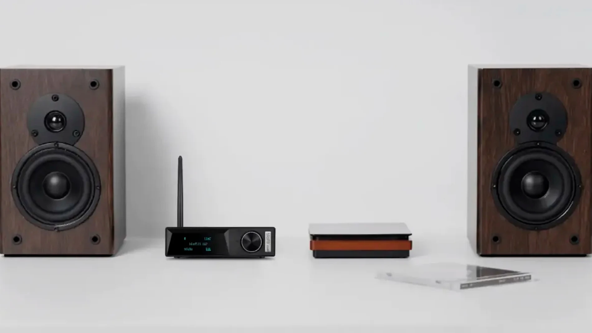 Dos altavoces estéreo de dos vías rodeando a un receptor Bluetooth integrado en un amplificador de Clase D