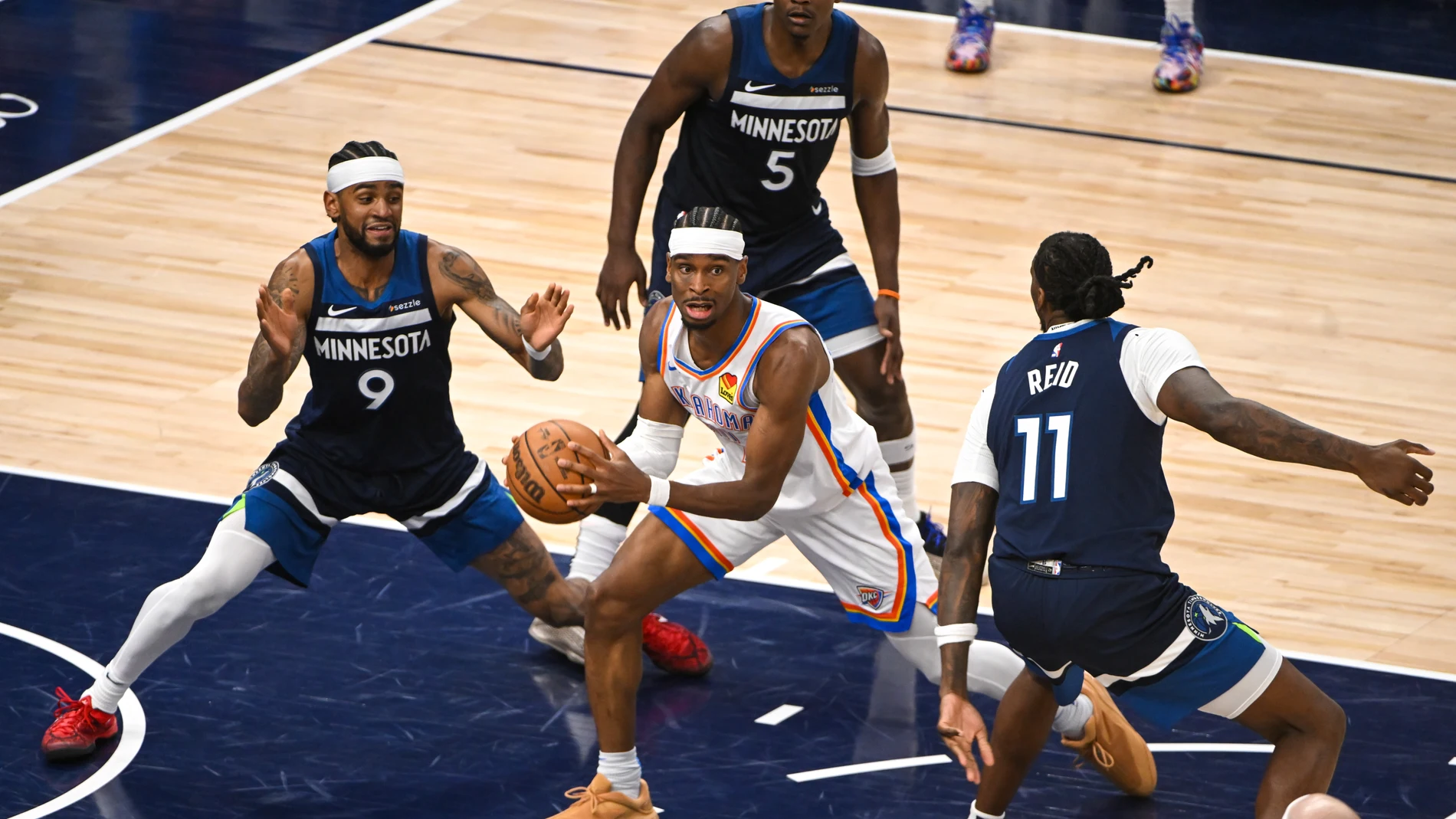 Tres jugadores de los Wolves intentan frenar a Shai Gilgeous-Alexander