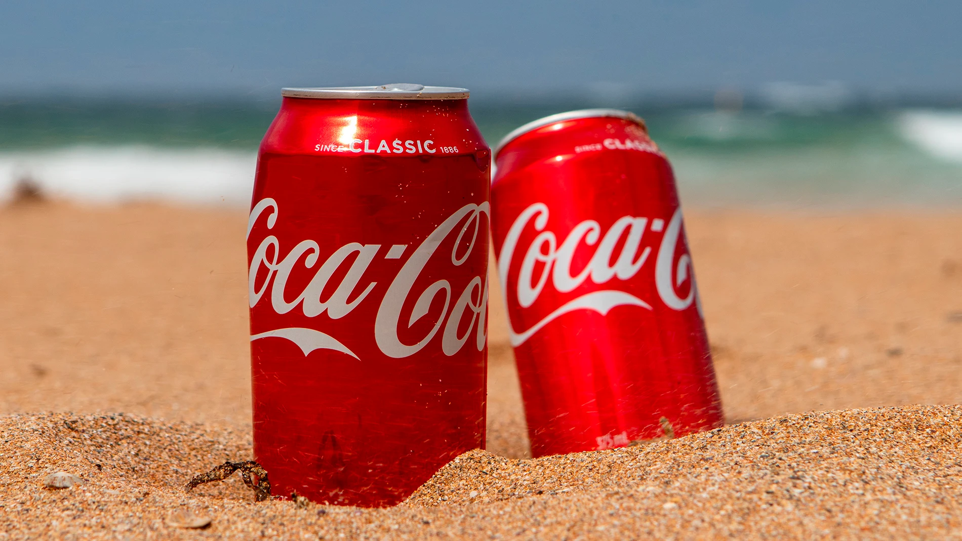 Dos latas de Coca-Cola en la playa