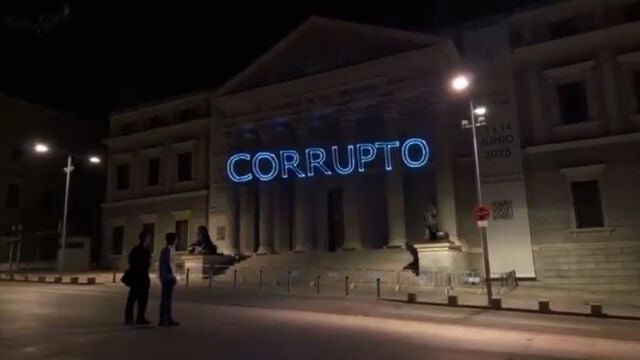Miembros de Hazte Oír proyectan sobre la fachada del Congreso el mensaje "Sánchez corrupto".