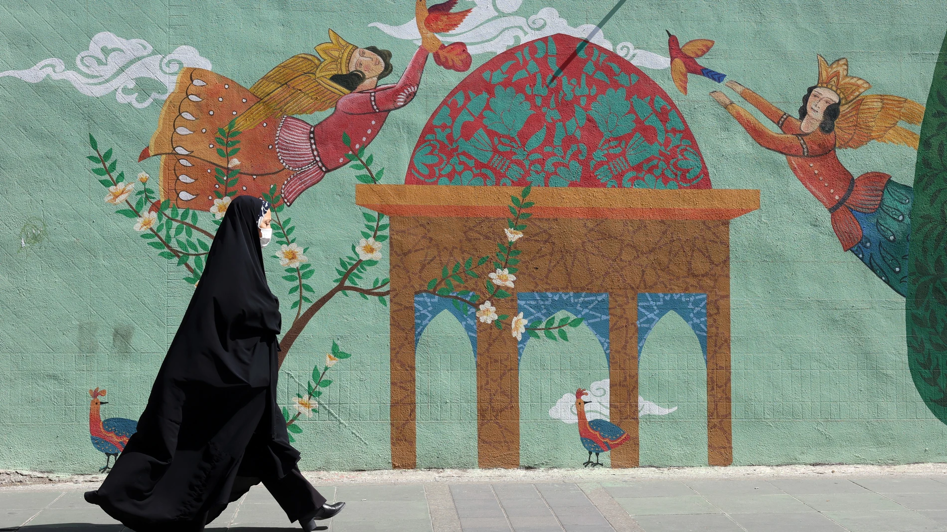 TEHRAN (IRAN(Islamic Republic Of)), 01/06/2025.- A veiled Iranian woman walks next to a wall painting on a street in Tehran, Iran, 01 June 2025. In a joint statement on 31 May 2025, the Iranian Foreign Ministry and the Iranian Atomic Organisation condemned International Atomic Energy Organisation (IAEA) reports against Iran, adding that accusations regarding alleged undeclared sites and activities from decades ago were baseless, and that they had cooperated by providing access, samples and in...