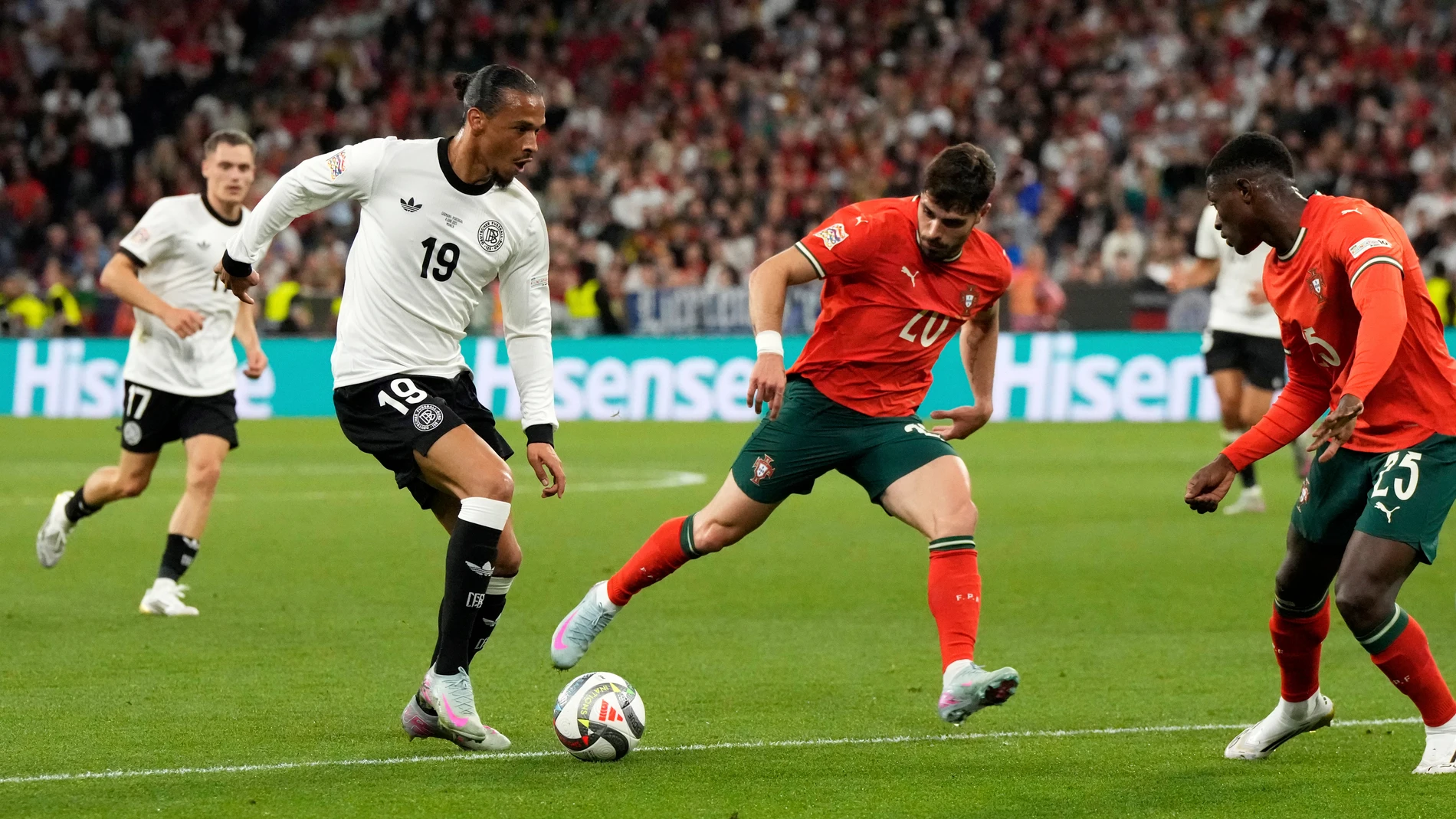 Germany's Leroy Sane tries to drive the ball past Portugal's Pedro Neto and Nuno Mendes, right, during the Nations League semifinal soccer match between Portugal and Germany at the Munich Football Arena, in Munich, Germany, Wednesday, June 4, 2025. (AP Photo/Martin Meissner)