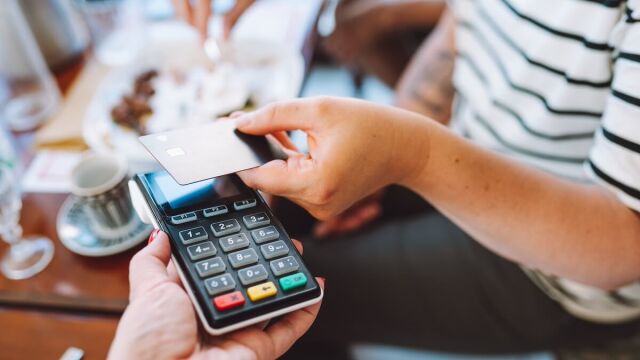 Una persona pagando con tarjeta de crédito en una cafetería
