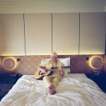 El músico maliense Salif Keita posa en una cama con su guitarra.