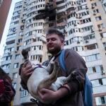 Un hombre lleva a su perro delante de un edificio residencial de varias plantas dañado tras un ataque ruso con drones en Kiev, 