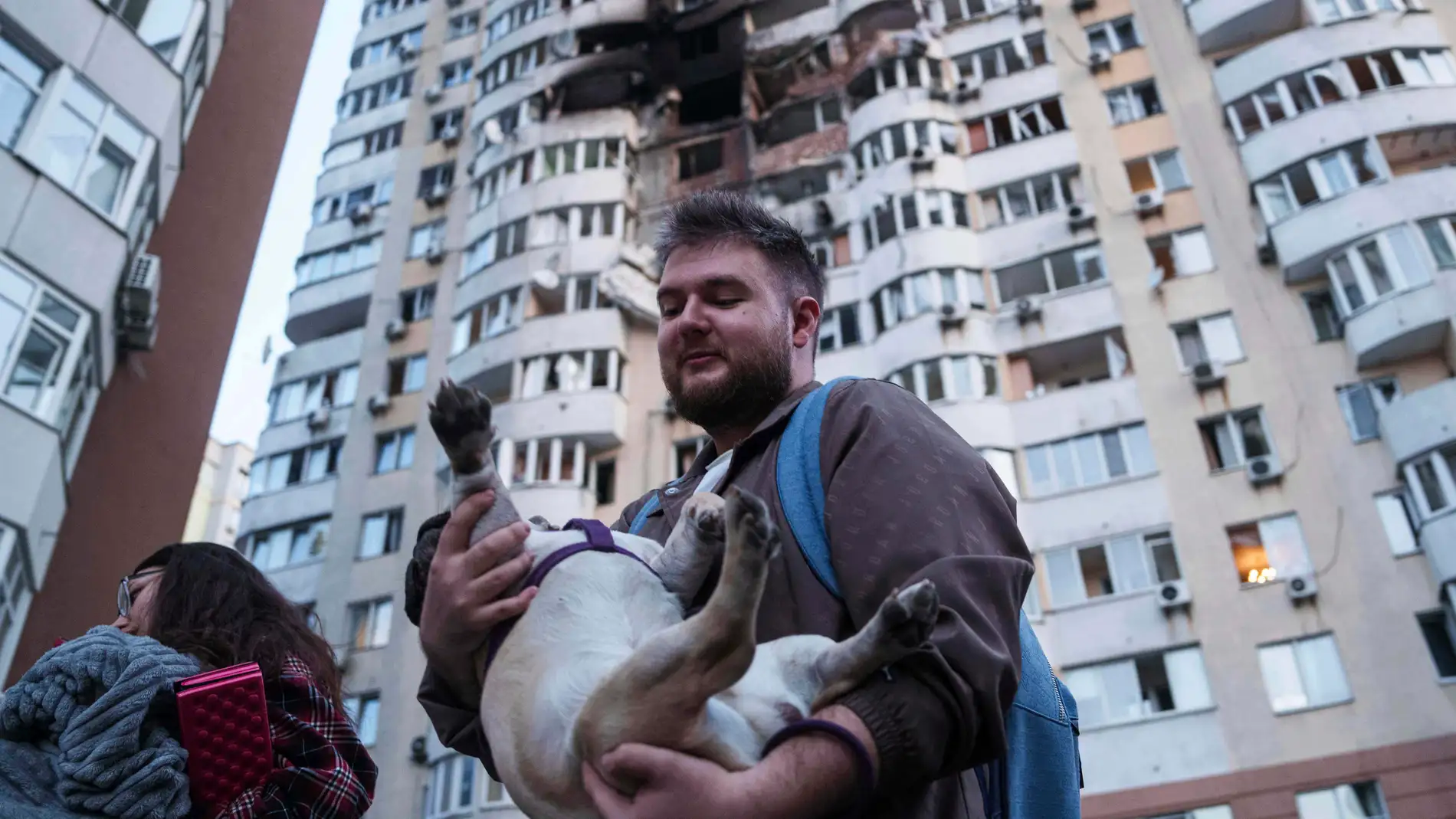 Un hombre lleva a su perro delante de un edificio residencial de varias plantas dañado tras un ataque ruso con drones en Kiev,