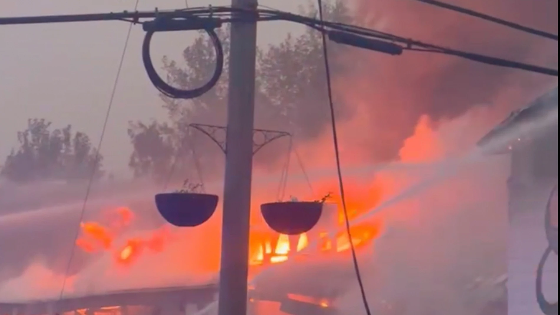 In this photo provided by Evan Bell firefighters combat the wildfires as they consumed Robertson Trading, a general store, in La Ronge, Saskatchewan on June 3, 2025. (Evan Bell via AP)