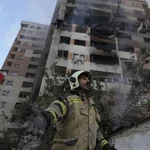 A firefighter calls out his colleagues at the scene of an explosion in a residence compound in northern Tehran, Iran, Friday, June 13, 2025.