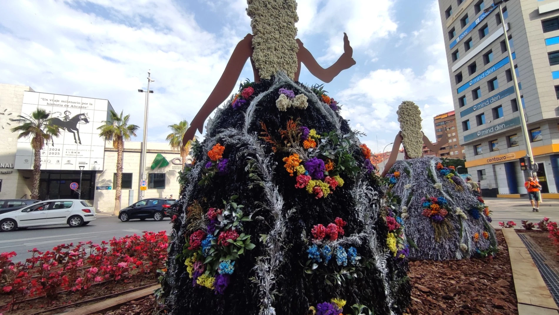 Faldas del traje de novia alicantina elaborados con flores; las figuras de las Belleas saludan a los pasajeros que llegan en tren a Alicante