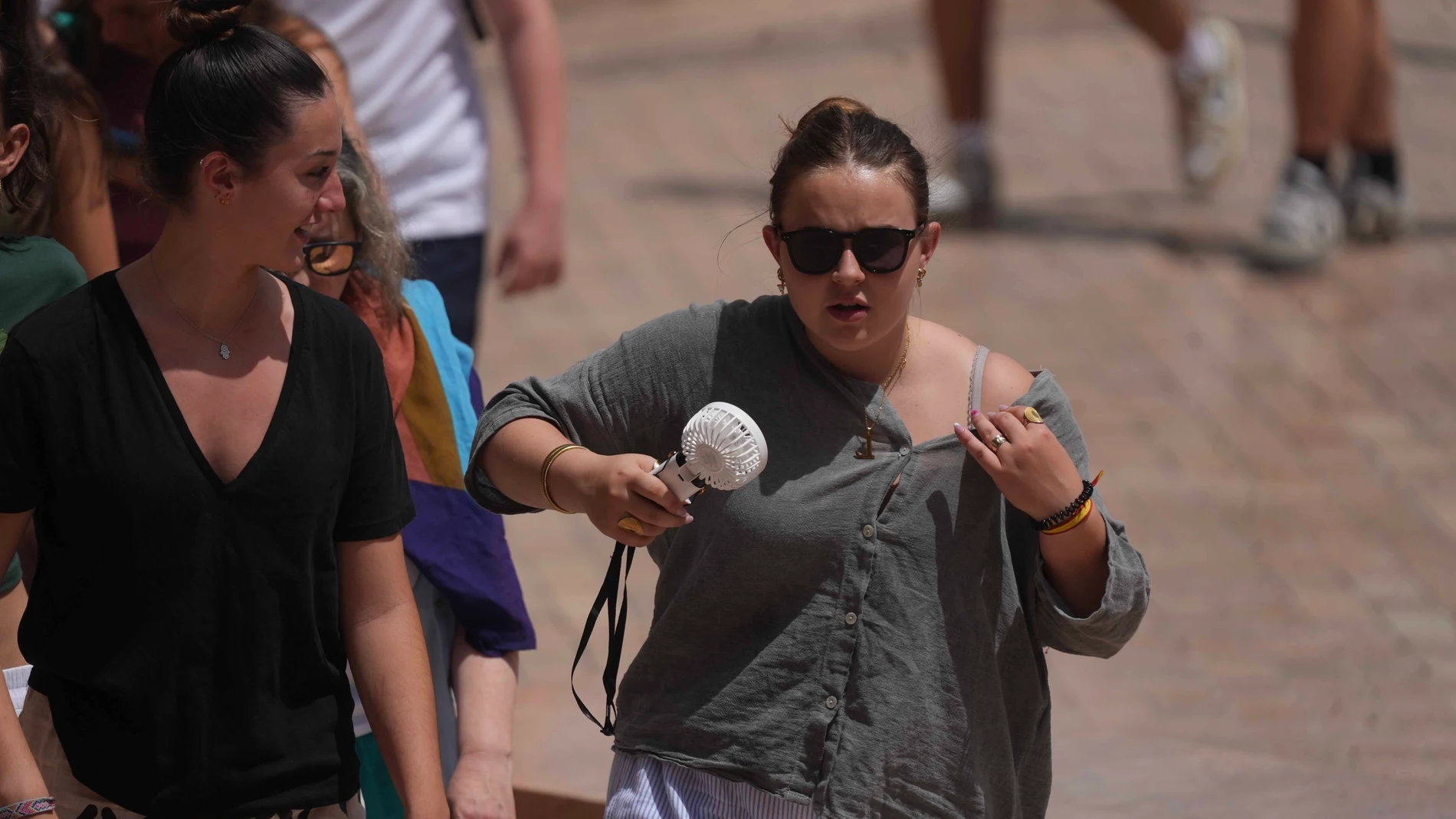 GRAFAND9459. CÓRDOBA, 18/06/2025.- Una turista se refresca con un mini ventilador mientras pasea por el Puente Romano de Córdoba este miércoles en el que la Agencia Estatal de Meteorología (Aemet) alerta de que el calor sofocante de estos días seguirá dejando noches tórridas en las que no se bajará de 25 grados y por el día las máximas superarán los 40 grados sobre todo en los valles del Guadalquivir y del Guadiana. EFE/ Rafa Alcaide