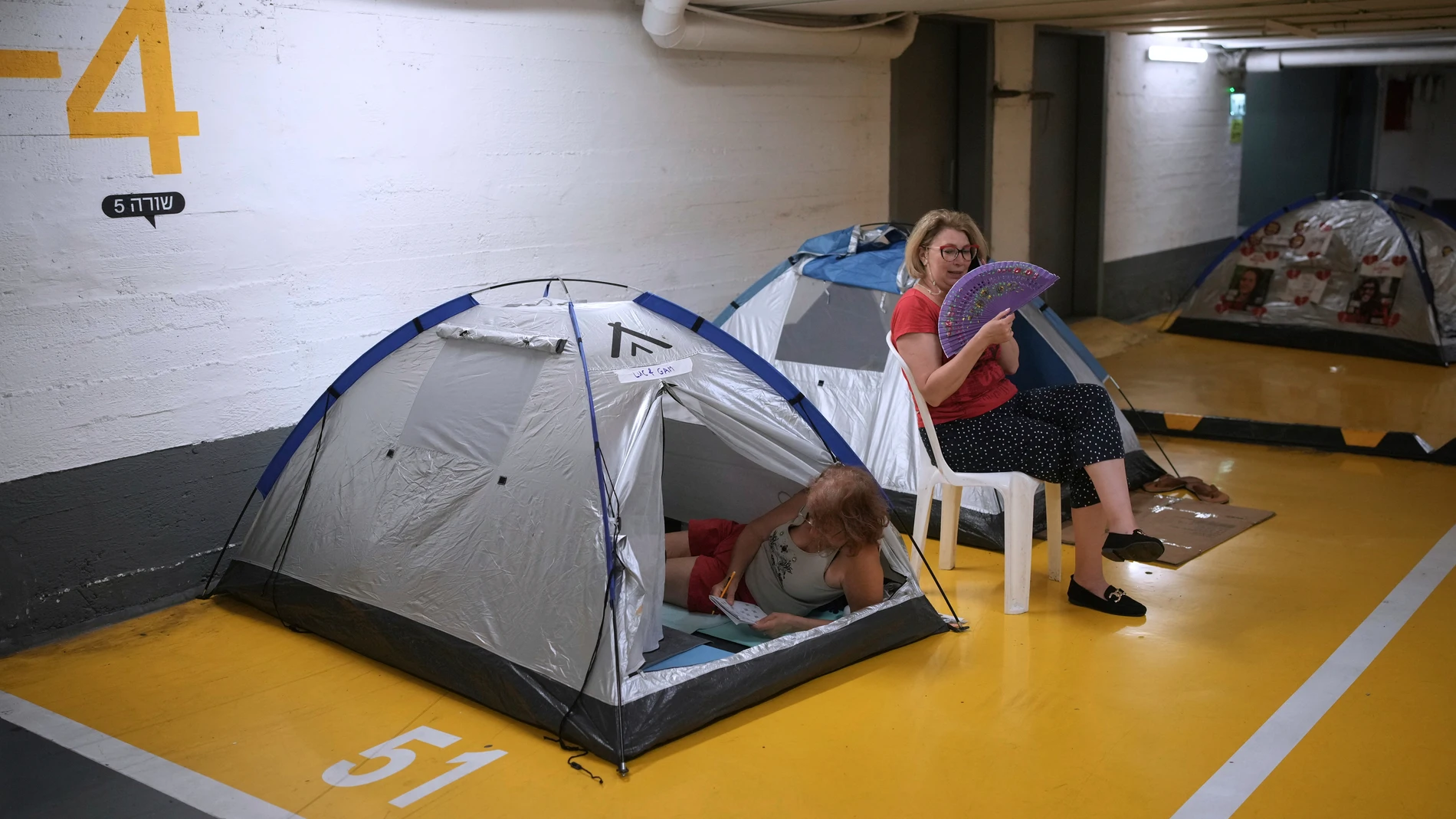 People take shelter in a parking garage as a precaution against possible Iran missile attacks, in Tel Aviv, Israel, Wednesday, June 18, 2025. (AP Photo/Ohad Zwigenberg)