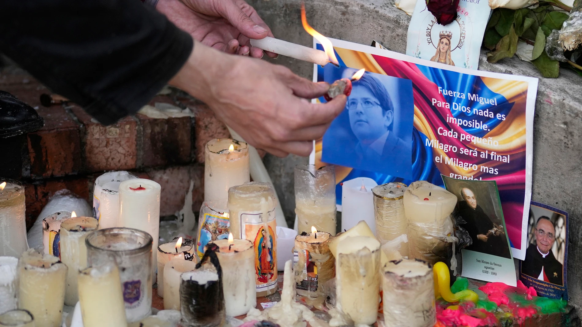 A man lights candles on an altar that was set up in honor of Colombian Senator Miguel Uribe Turbay who is being treated after he was shot at a political rally, in Bogota, Colombia, Wednesday, June 18, 2025. (AP Photo/Fernando Vergara)