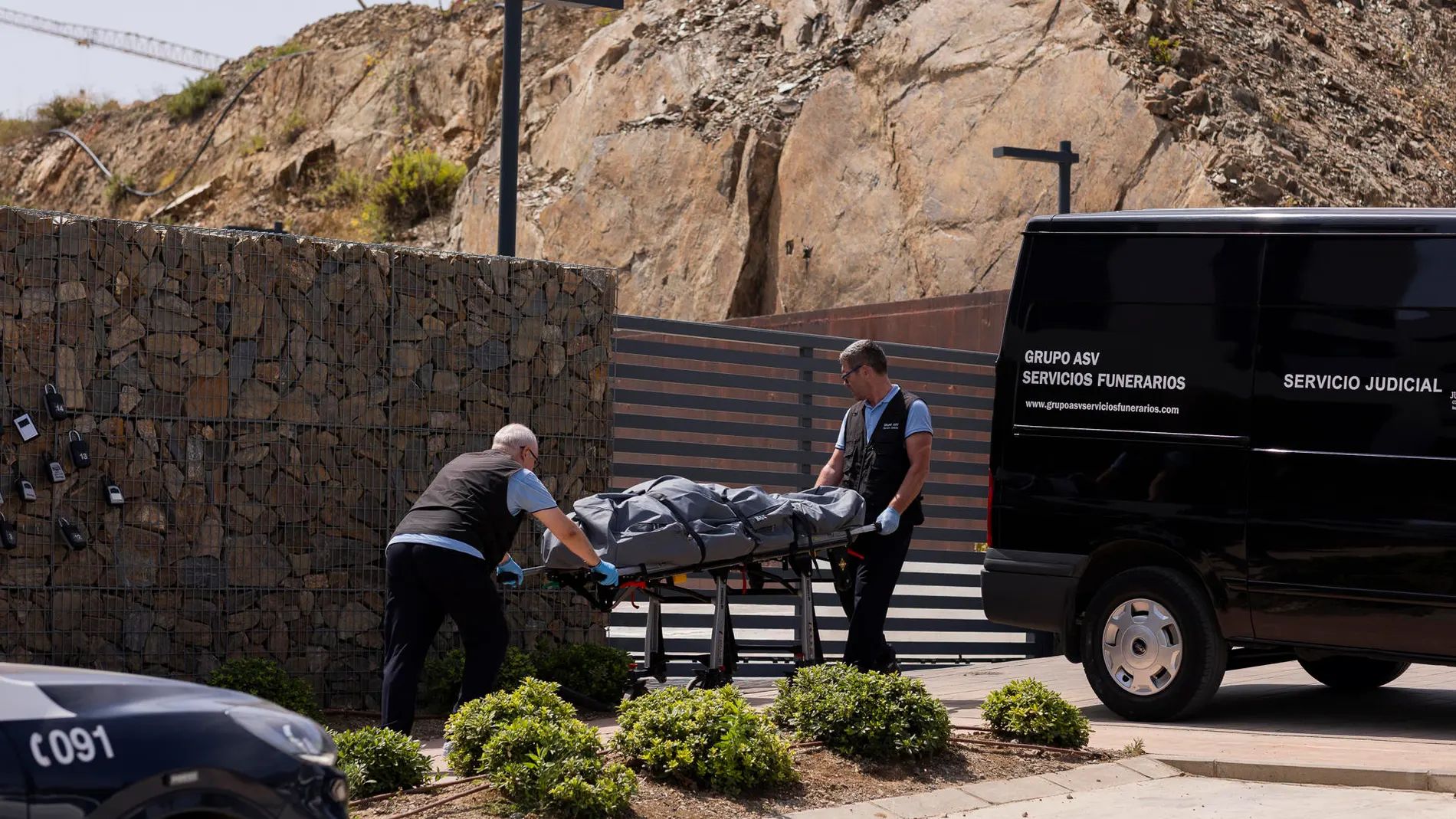 Dos operarios de la funeraria trasladan uno de los cuerpos sin vida en la urbanización Higuerón West de la localidad malagueña de Fuengirola