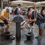 Turistas en plena ola de calor en agosto en la ciudad de Madrid intentan refrescarse en las fuentes de agua in