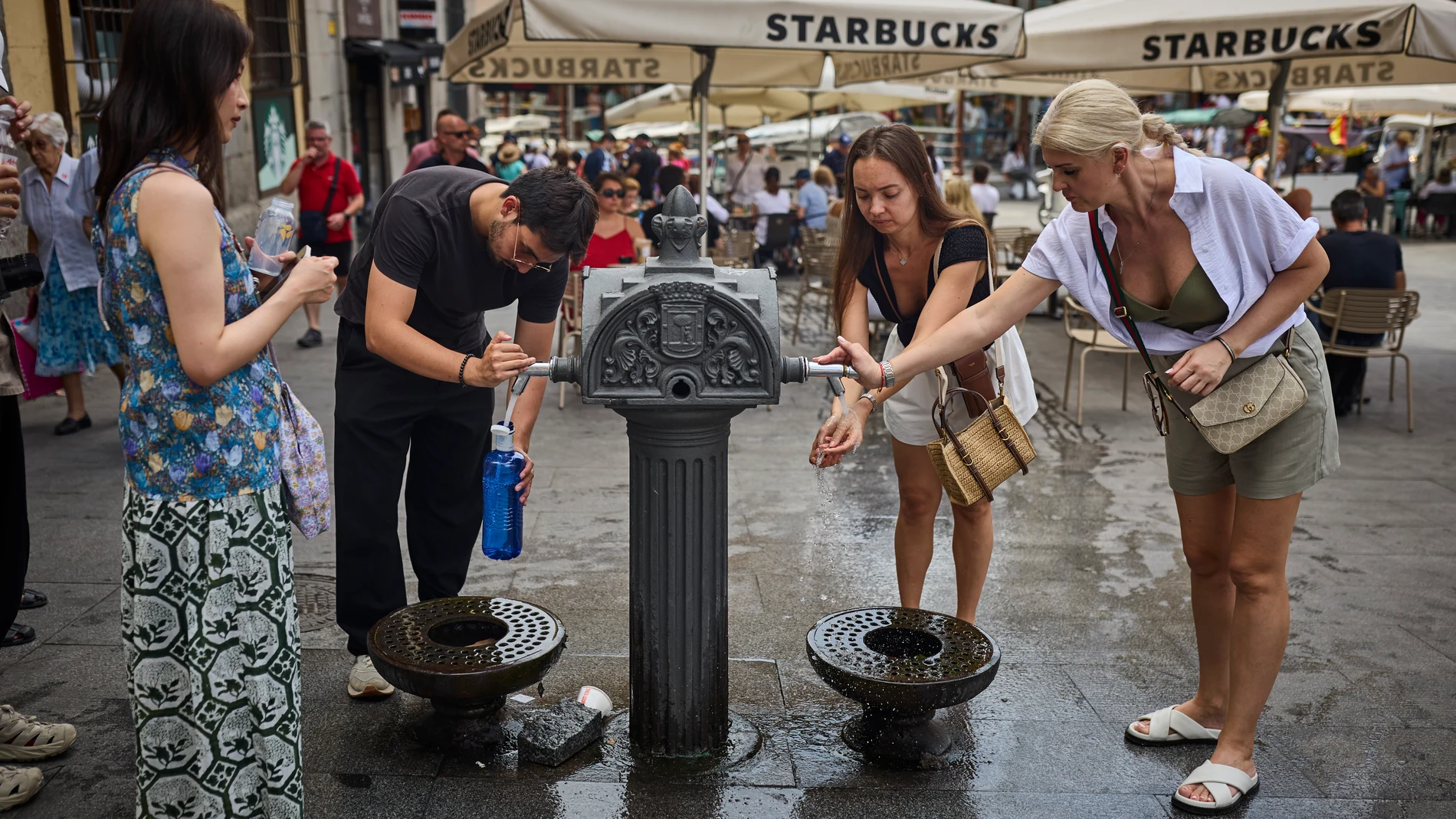 Turistas en plena ola en la ciudad de Madrid intentan refrescarse en las fuentes de agua
