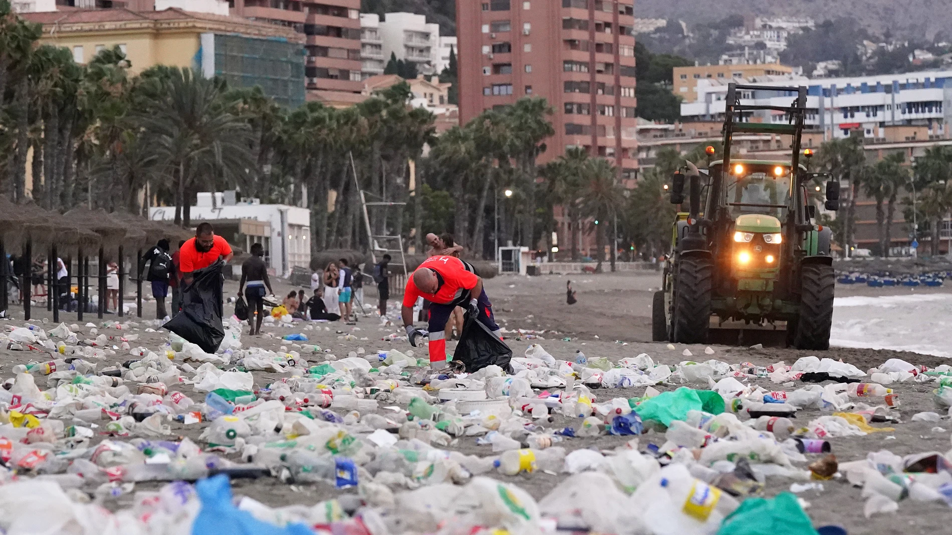 Miembros del servicio de limpieza municipal de Málaga recogen restos de basura en la playa de La Malagueta tras la celebración de la noche de San Juan