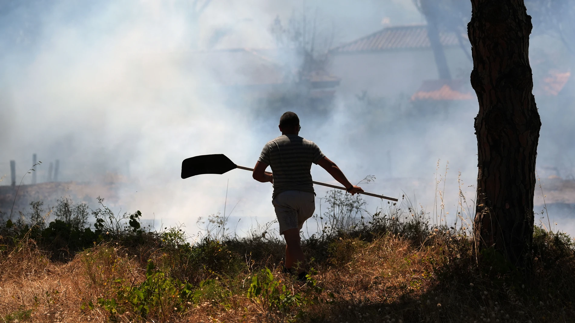 GRAFAND9846. CHICLANA DE LA FRONTERA (CÁDIZ), 01/07/2025.- Un hombre observa las casas que se han desalojado de manera preventiva mientras los efectivos del Infoca y del Consorcio Provincial de Bomberos trabajan en la extinción del incendio de pastos en Chiclana de la Frontera (Cádiz), según han informado fuentes del Consorcio Provincial de Bomberos.EFE/Román Ríos