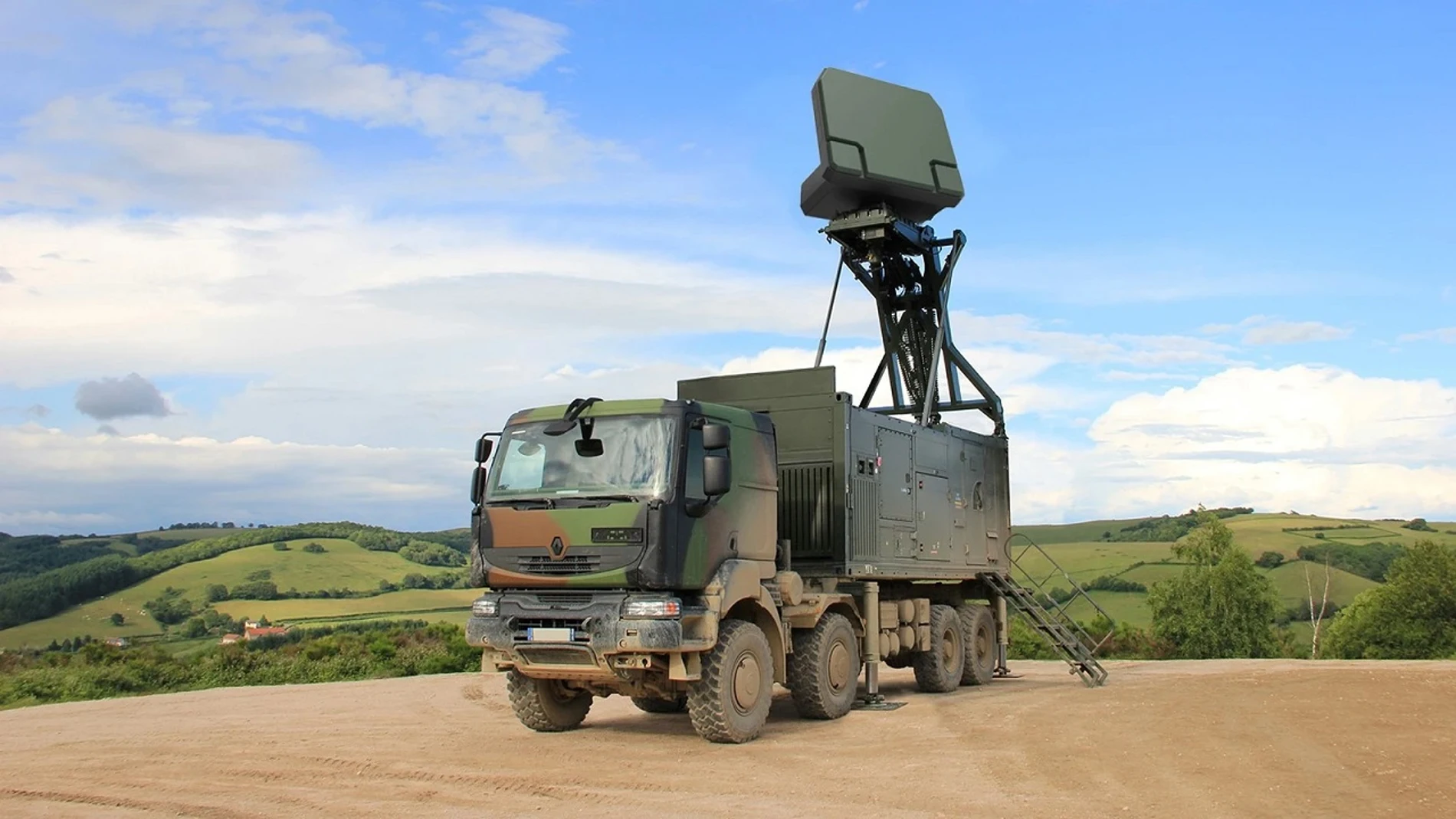 Un camión militar de color camuflaje verde en el que la parte trasera dispone de un contenedor que despliega una estación de radar
