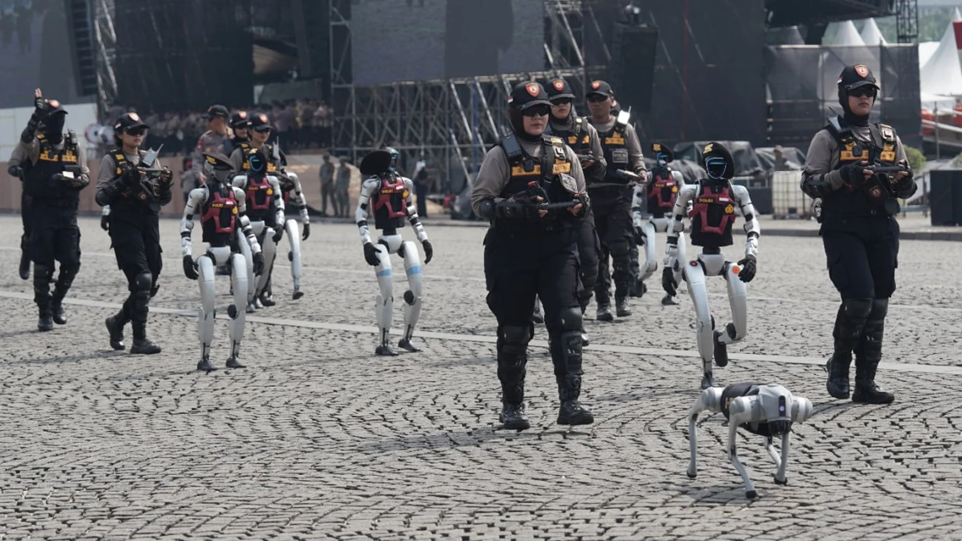 Aparece un desfile policial en una calle donde se puede ver a oficiales de cuerpos de seguridad acompañados de robot humanoides y perros robot