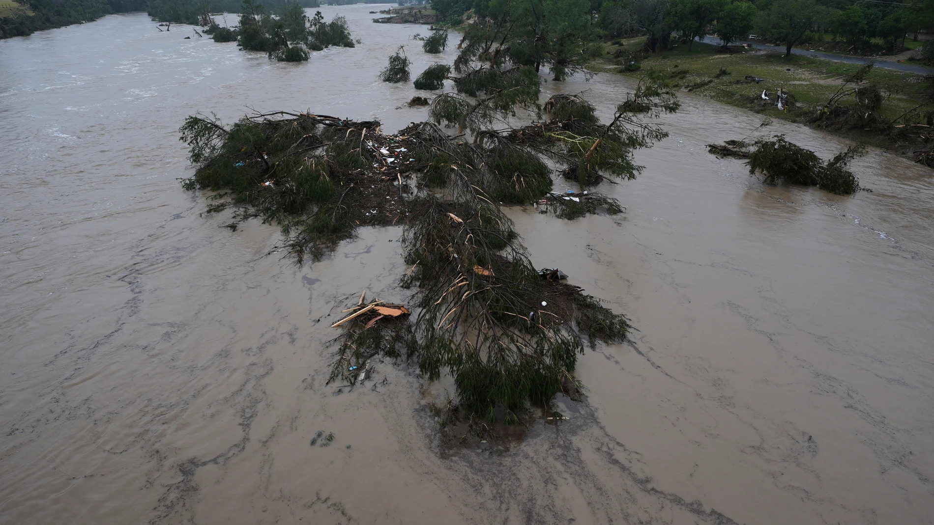 A raging Guadalupe River leaves fallen trees and debris in its wake, Friday, July 4, 2025, in Kerrville, Texas. (AP Photo/Eric Gay)