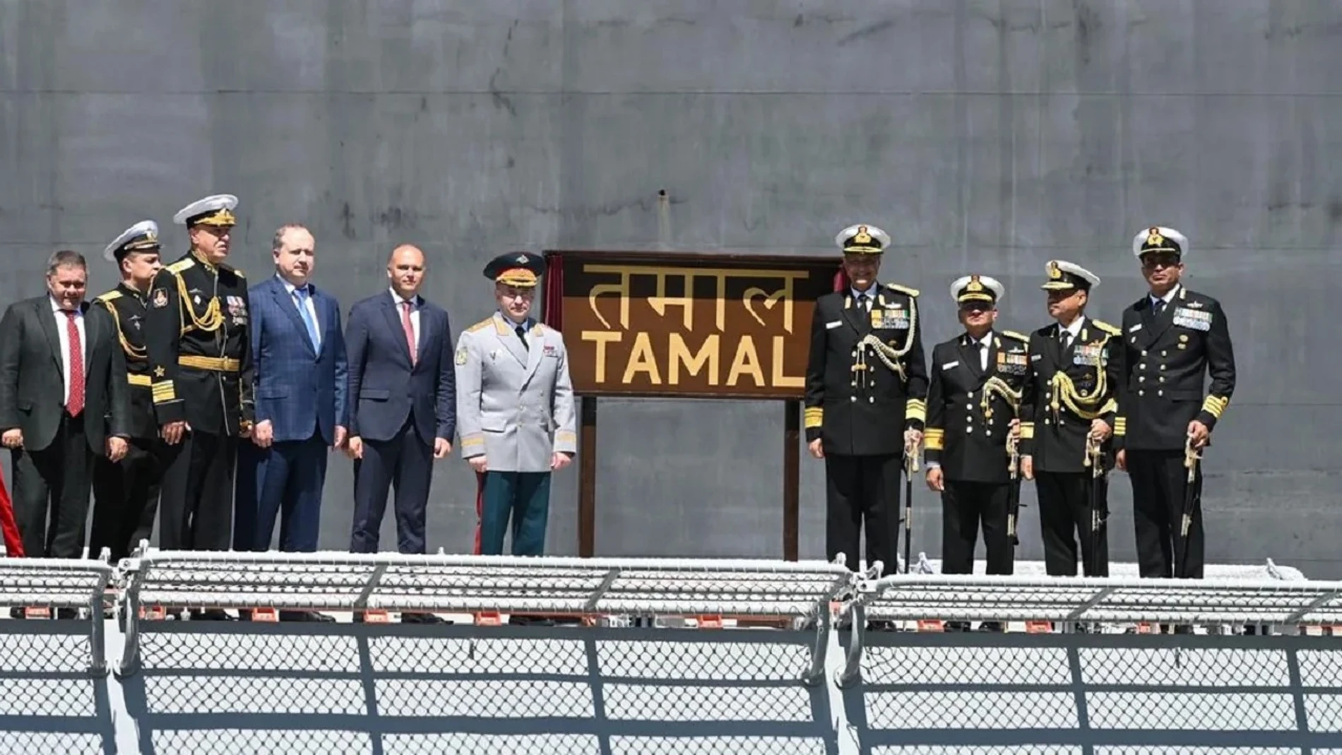 Aparecen un grupo de hombres con uniformes militares y trajes