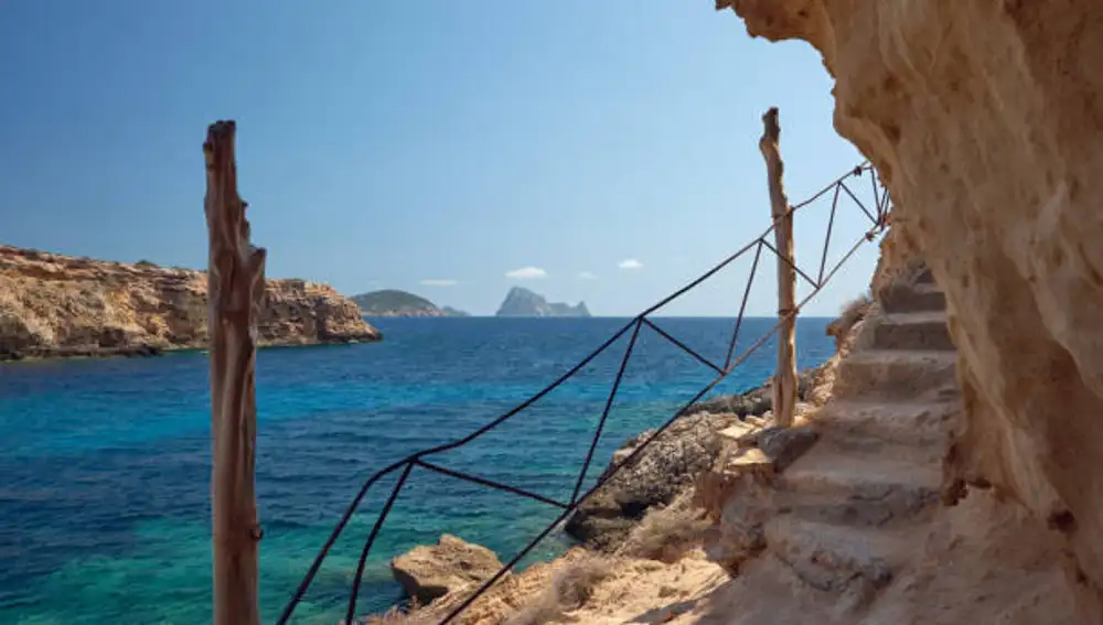 Las escaleras que bajan hasta la cueva, con el islote de es Vedrà de fondo