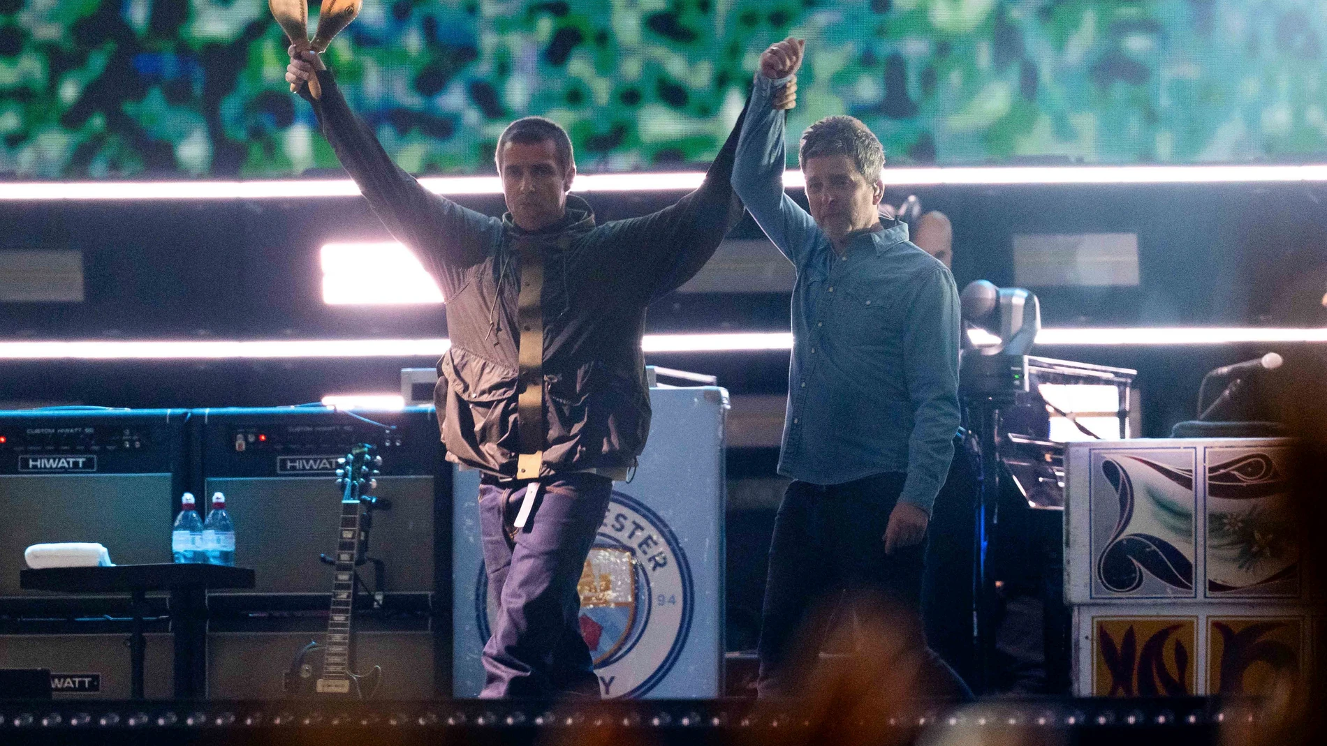 Liam Gallagher, left, holds the hand aloft of Noel Gallagher from the band Oasis as they perform during their reunion concert on Friday, July 4, 2025, in Cardiff. (Photo by Scott A Garfitt/Invision/AP)