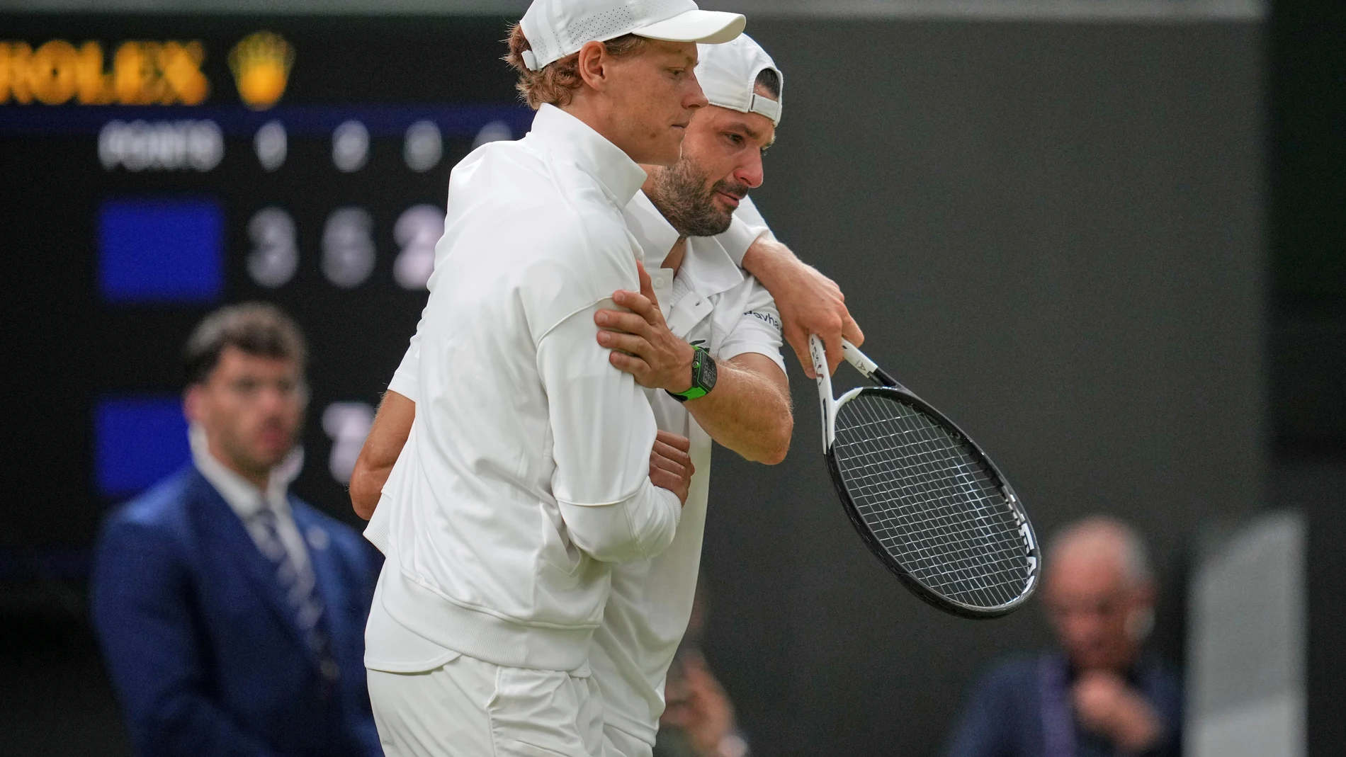 Italy's Jannik Sinner, left, assists Bulgaria's Grigor Dimitrov after he went down with an injury which forced him to retire from a fourth round men's singles match at the Wimbledon Tennis Championships in London, Monday, July 7, 2025. (AP Photo/Kin Cheung)
